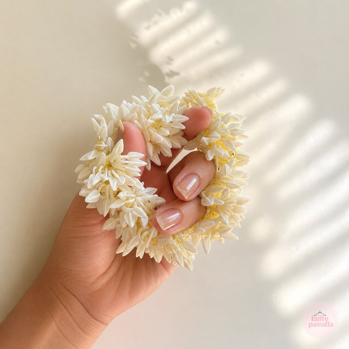 Hand holding a small bouquet of white flowers against a light background